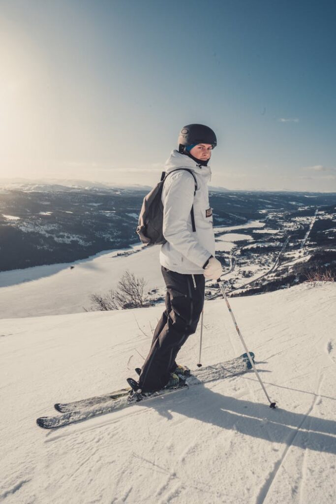 A skier in winter clothing enjoying a sunny day on a snowy mountain slope.